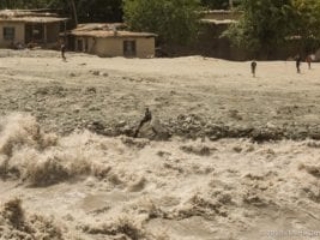 Across the river: Afghan man sitting on a rock